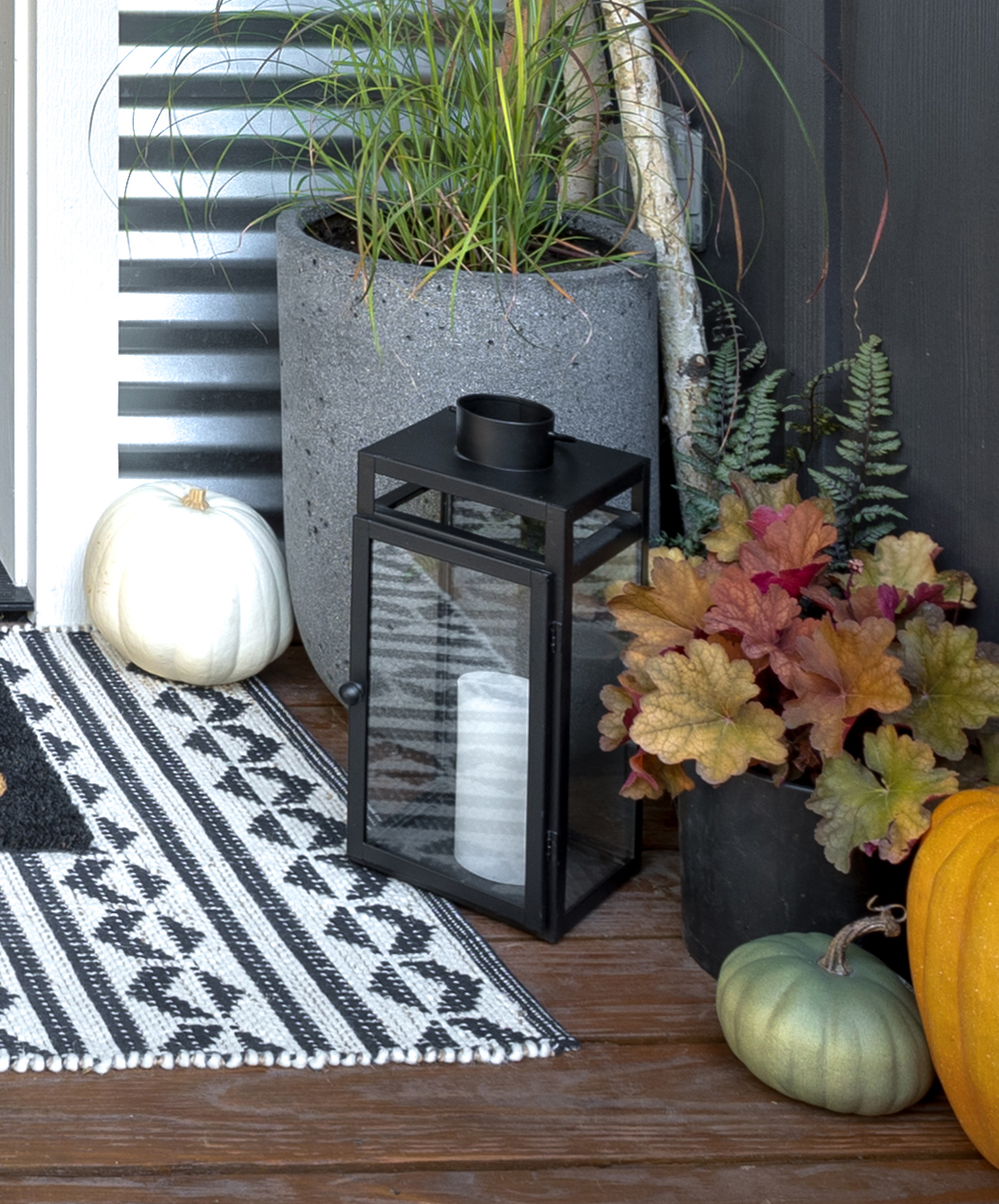 A black lantern with fall decorations around it