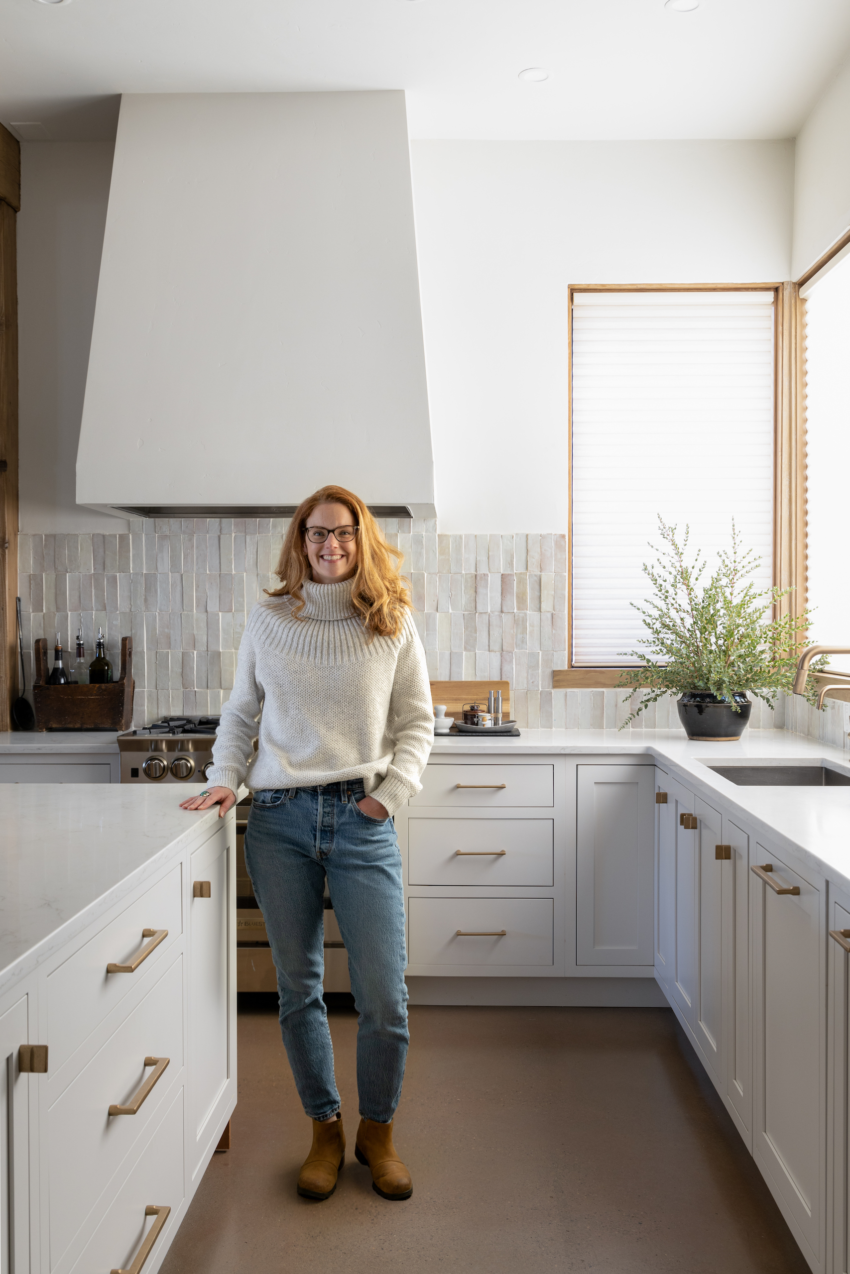 Ashley Neff smiling and standing in a beautiful white kitchen 